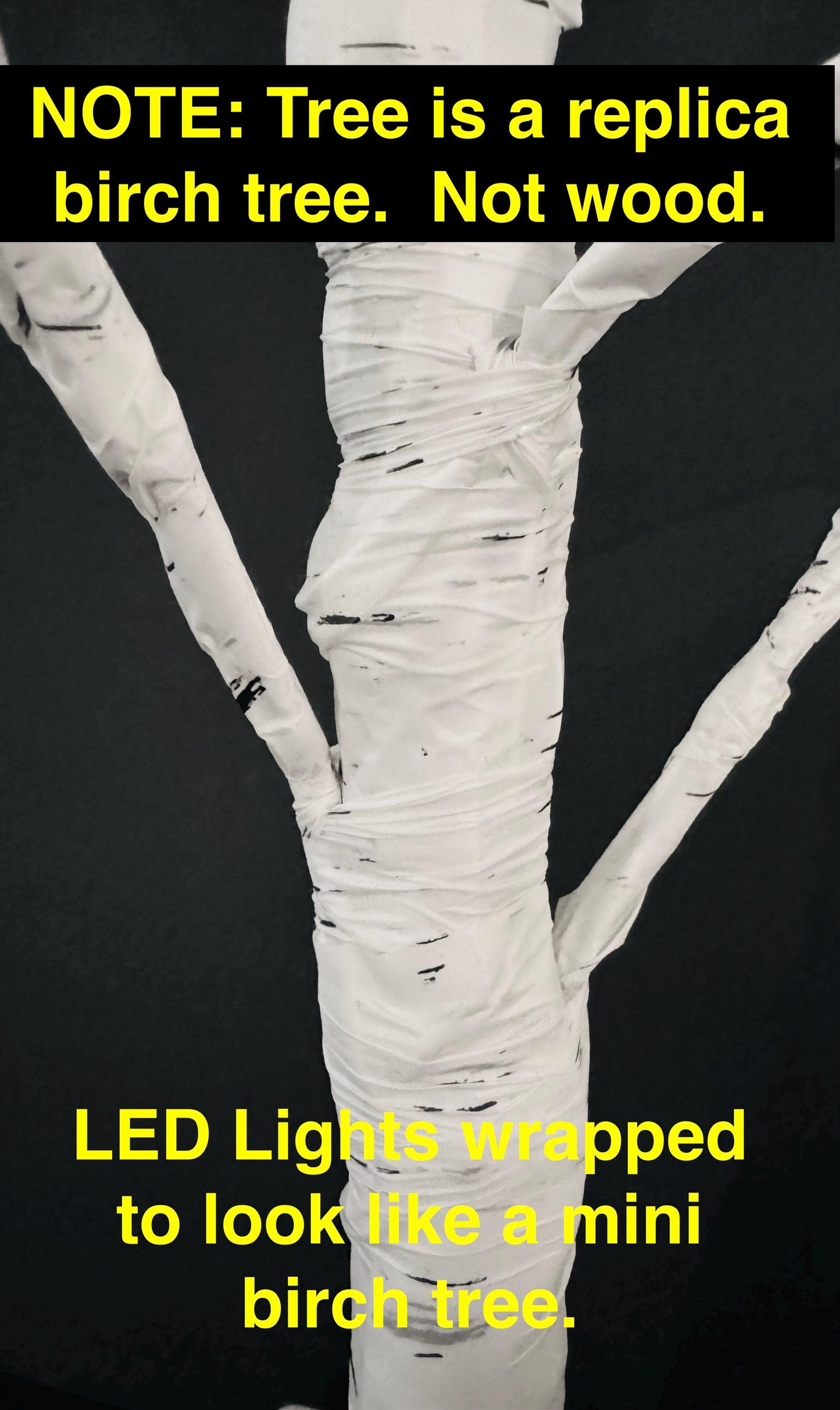 Replica birch tree with LED lights wrapped around it on a black background.