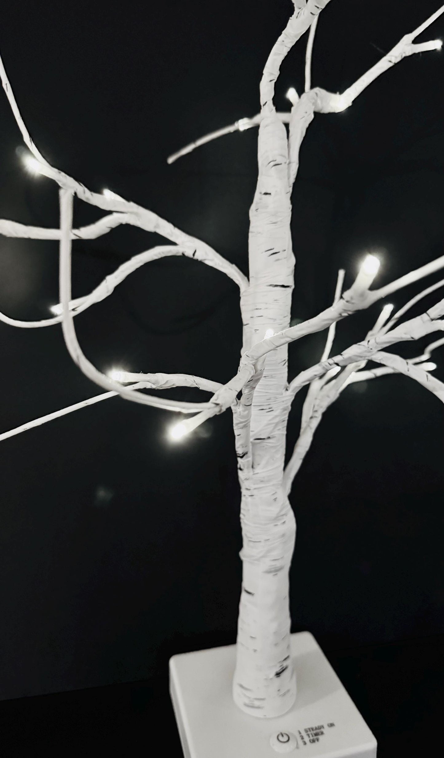 Decorative white tree with lights against a black background